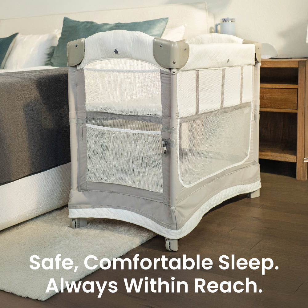 Mother reaching to her baby in the Mini Ezee 3-in-1 Co-Sleeper beside her bed