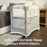 Mother reaching to her baby in the Mini Ezee 3-in-1 Co-Sleeper beside her bed