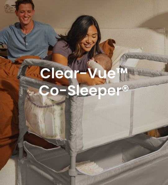 A gray and white Clear-Vue Co-Sleeper crib bed with a mesh side panel, shown in a bedroom setting with a smiling couple and baby in bed. The text 'Clear-Vue Co-Sleeper' is overlaid on the center.