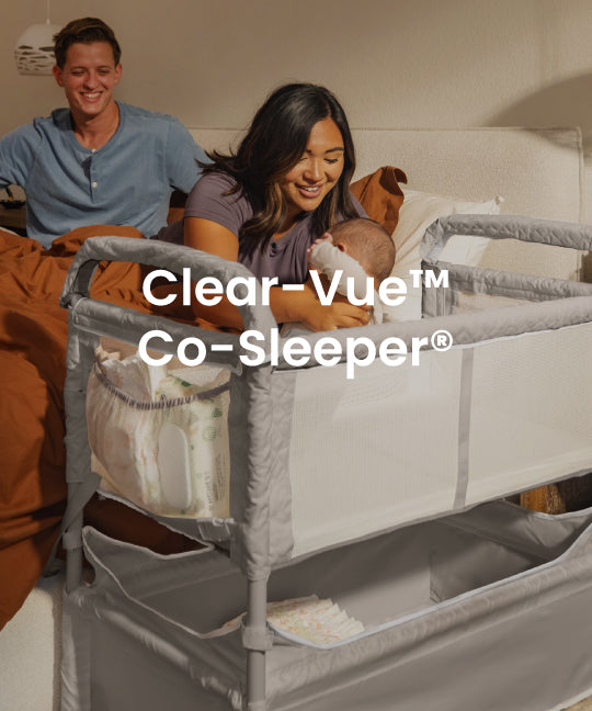 A gray and white Clear-Vue Co-Sleeper crib bed with a mesh side panel, shown in a bedroom setting with a smiling couple and baby in bed. The text 'Clear-Vue Co-Sleeper' is overlaid on the center.